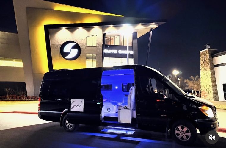 The black Sprinter arriving at a venue at night with the door open and the cabin glowing blue
