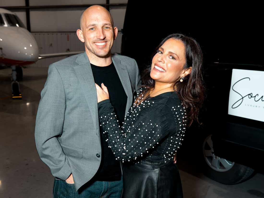 Jack and Jenna Harkreader, owners of Social Luxury Sprinter, standing beside their black Mercedes Sprinter